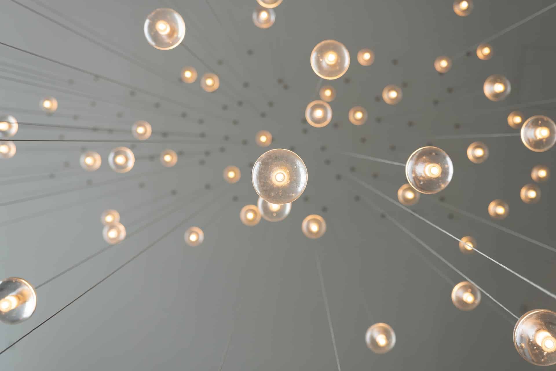 Image shows lightbulbs hanging from a ceiling, illustrating innovation and change.