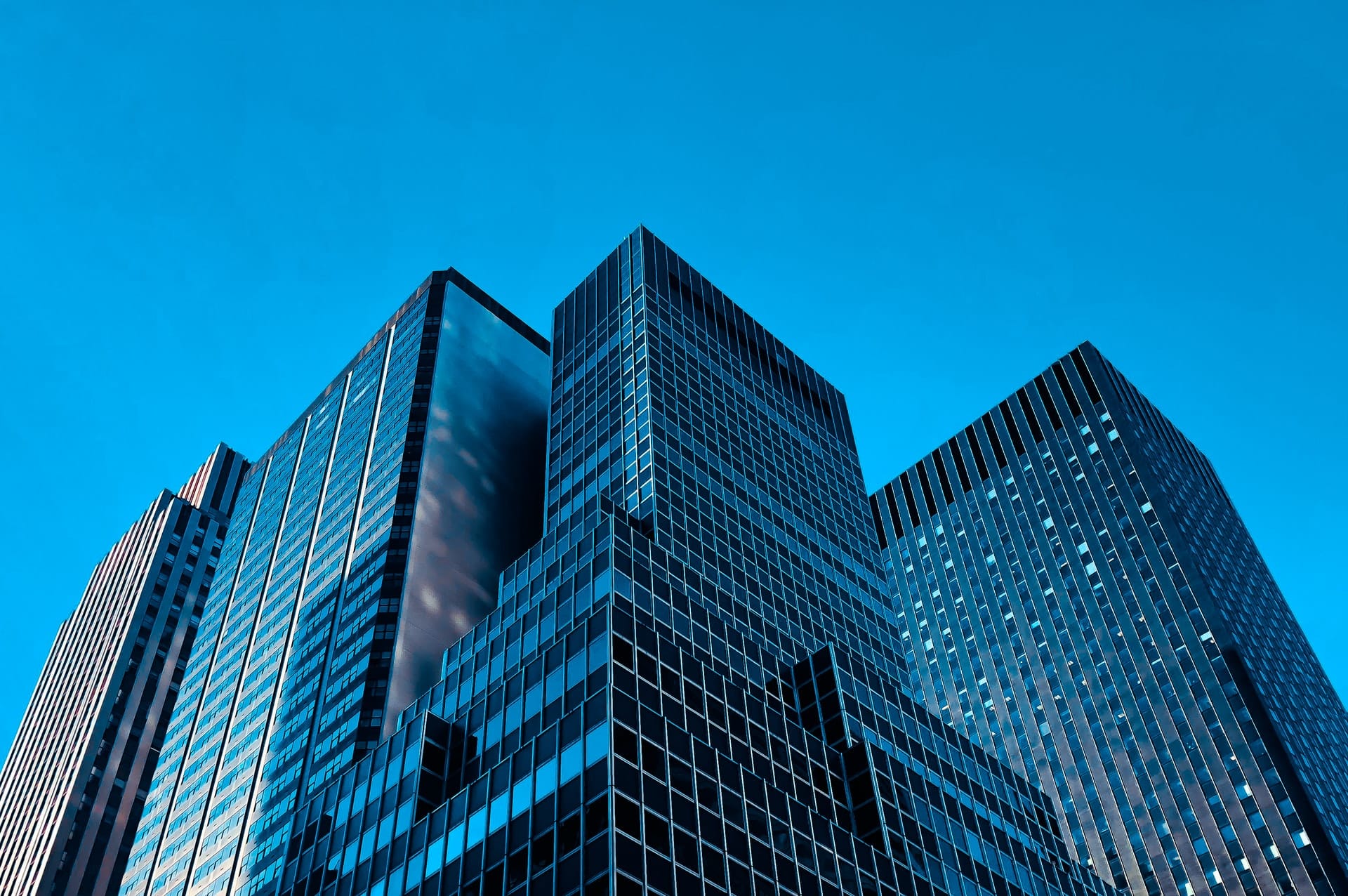 Image shows skyscrapers against a blue sky, illustrating the concept of companies applying ESG standards.
