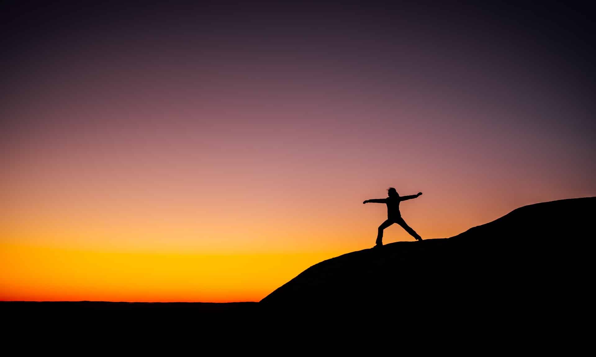 Image shows someone doing a yoga pose at sunset, illustrating the fact that health is gold.