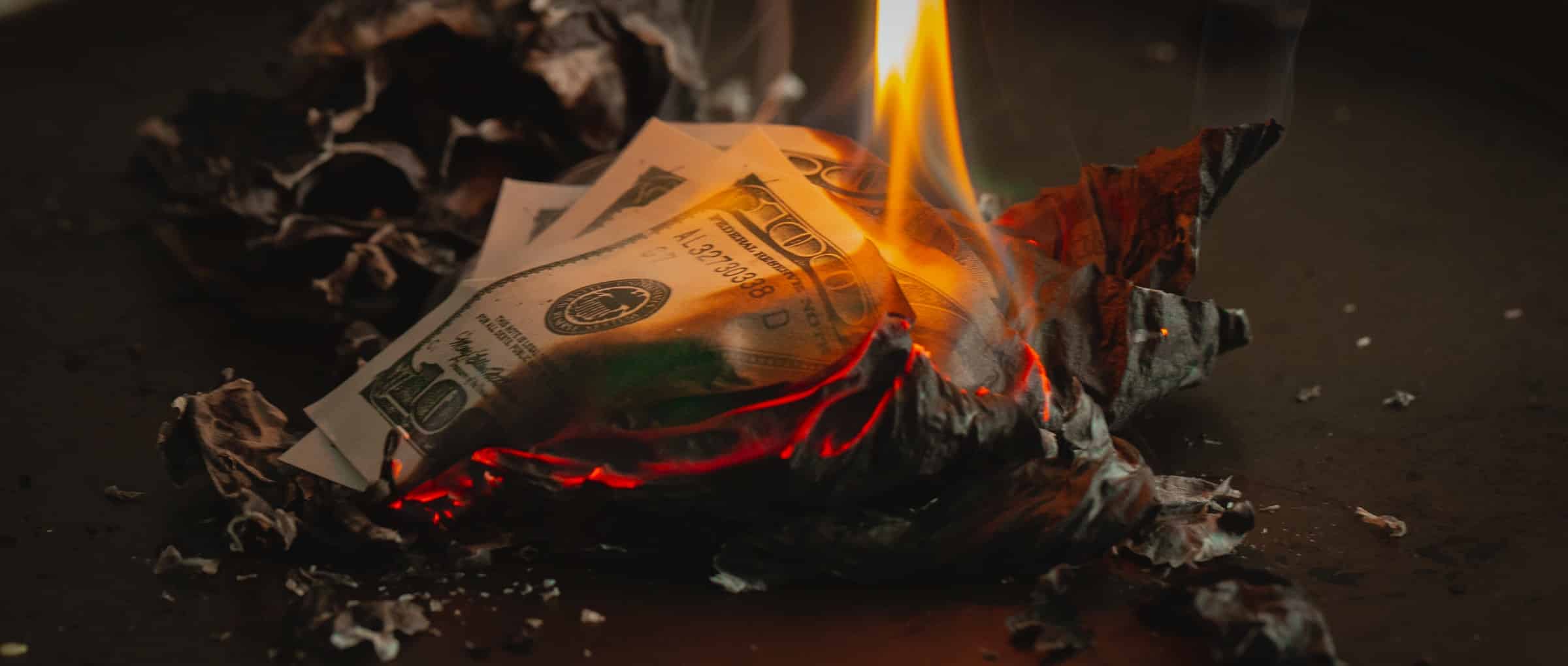 Money is burning and lying on top of ash to show a burn rate of cash