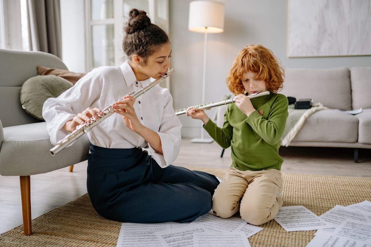 In this image, we see a woman teaching a kid how to play the flute, reminding us of a mentorship relationship.