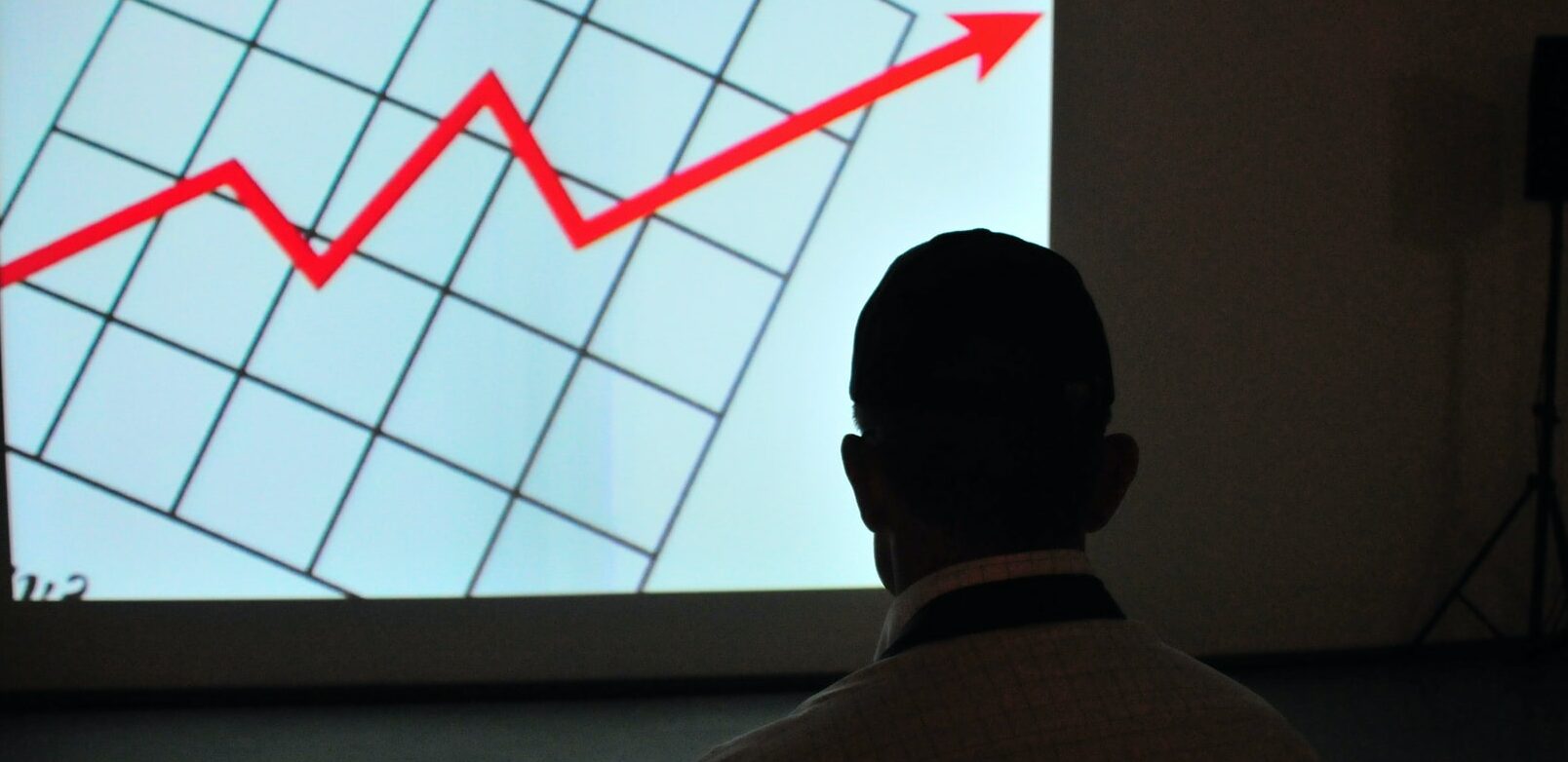 man looking at financial graph projected on the wall